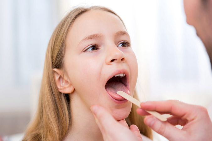 Pediatrician checking tonsils