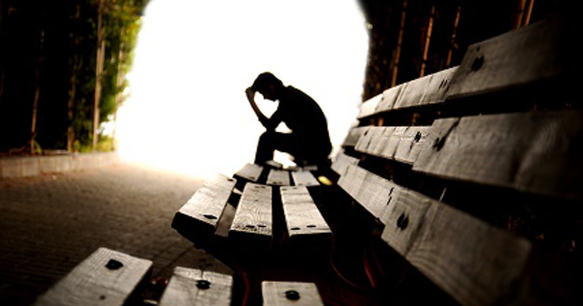 depressed person sitting on a bench 